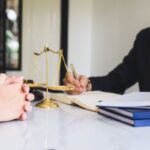 Advogado e cliente discutindo honorários sucumbenciais com balança da justiça
