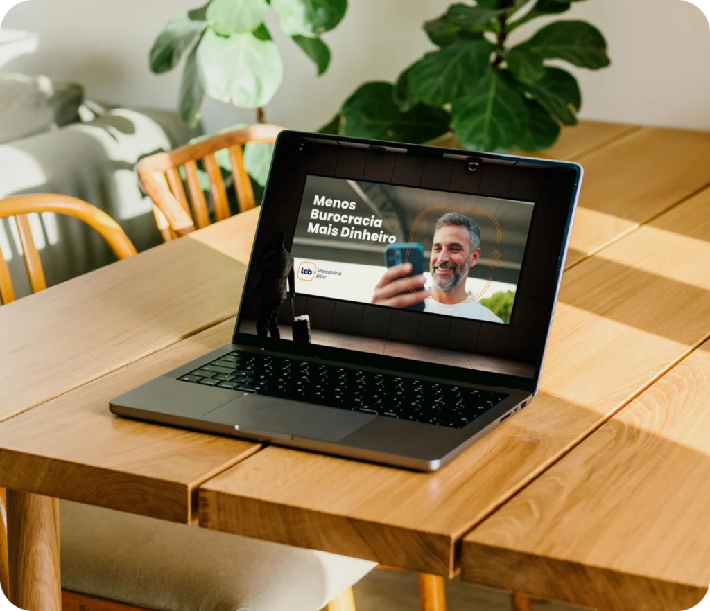 Laptop exibindo vídeo "Menos Burocracia Mais Dinheiro" com homem sorrindo